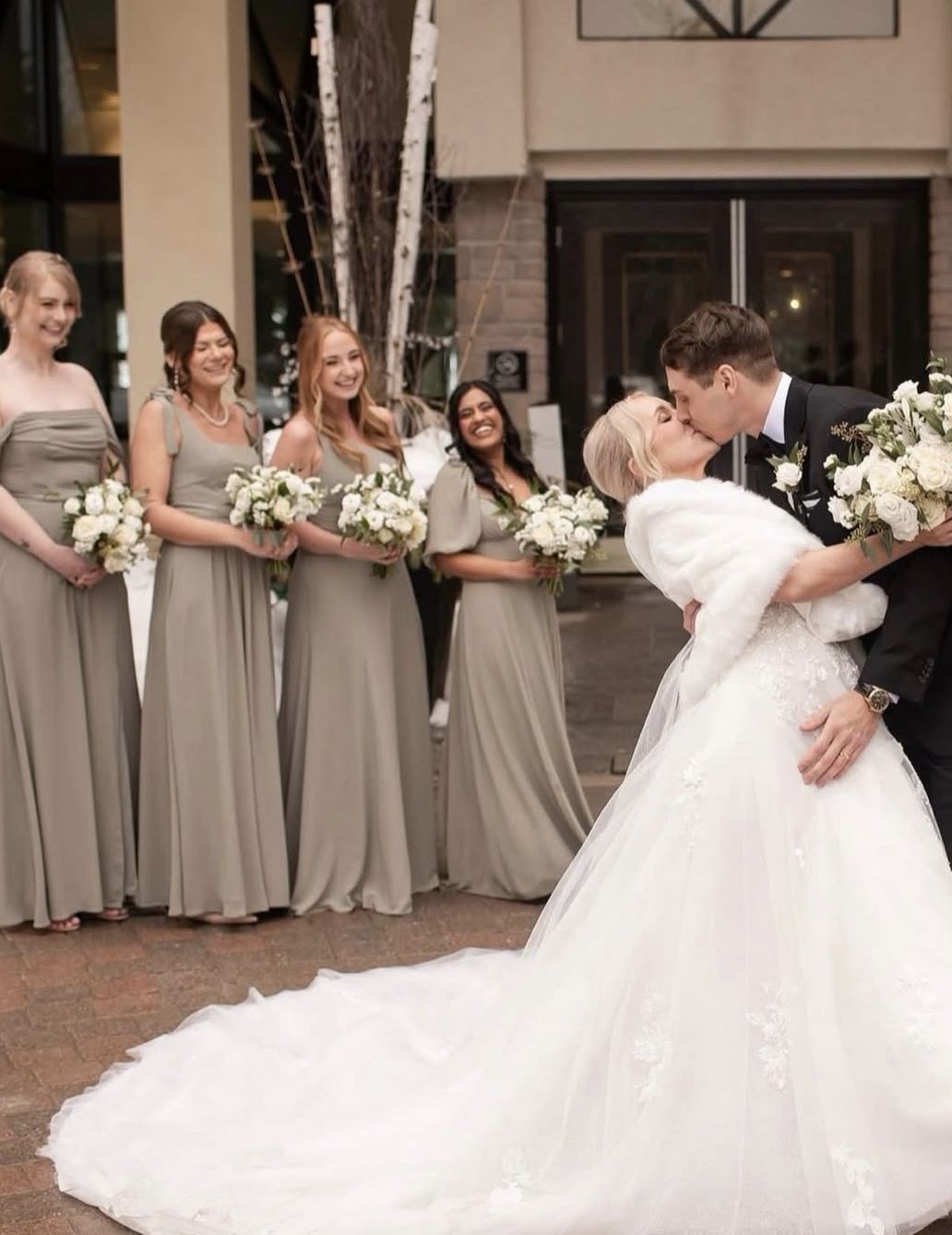 Newlyweds kissing in front of the bridal party