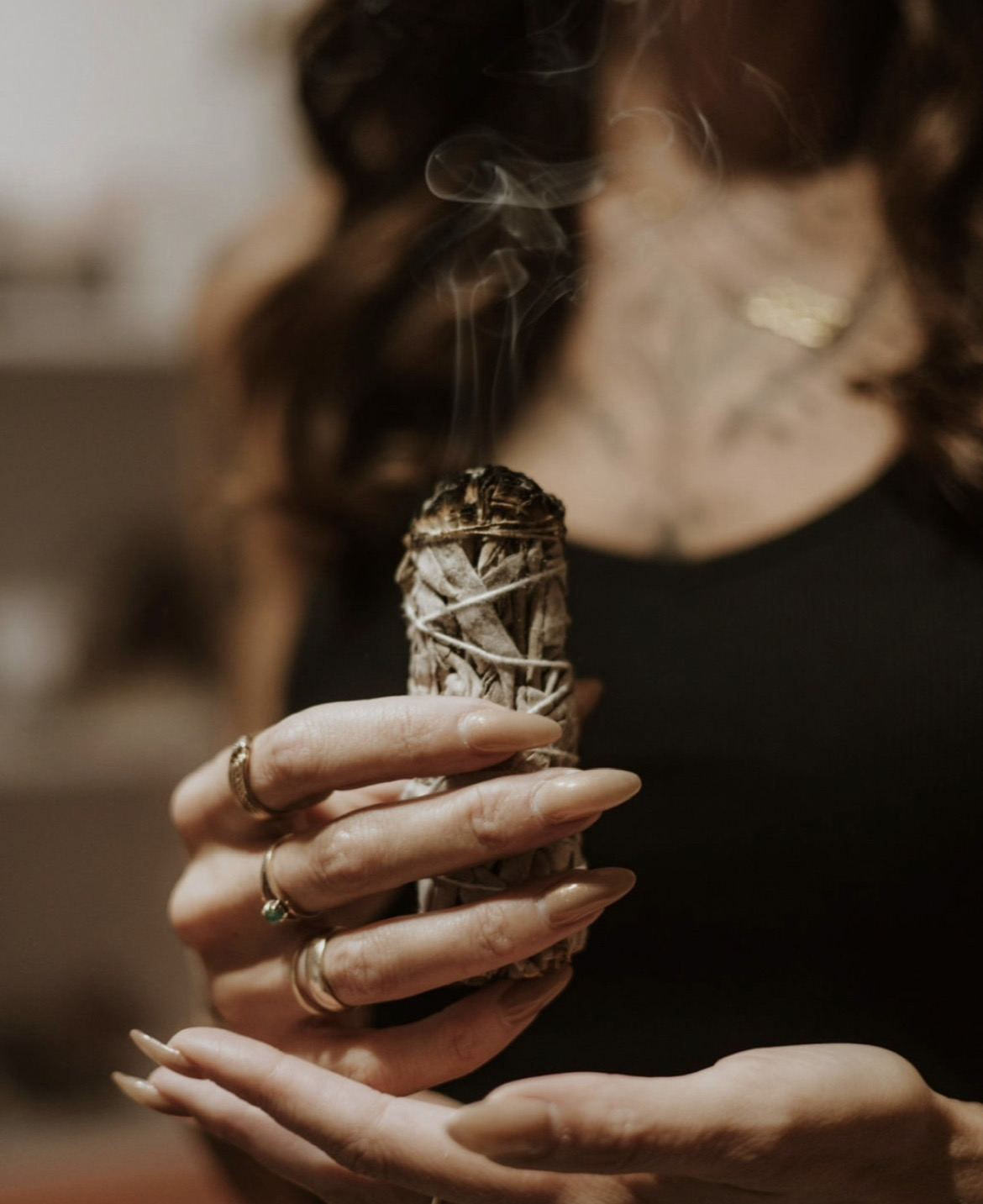 Hands holding a smoking sage bundle